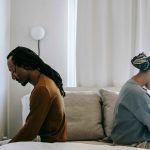 Man and woman sitting back-to-back, symbolizing emotional distance and grief after divorce or loss of a spouse