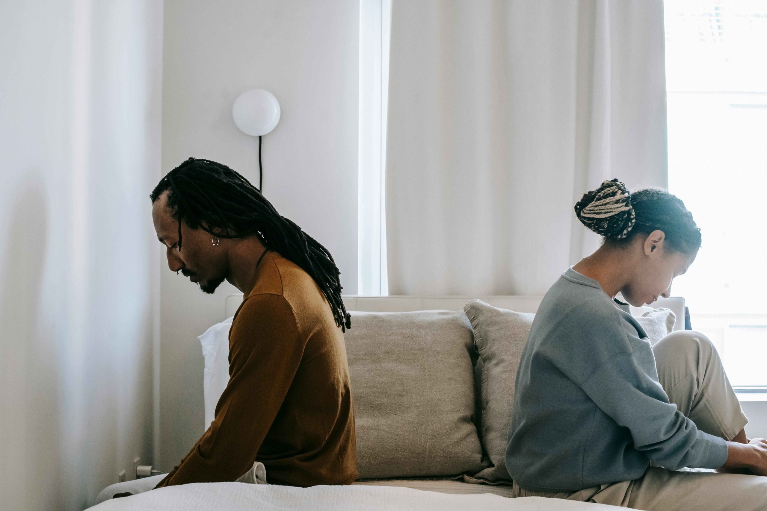 Man and woman sitting back-to-back, symbolizing emotional distance and grief after divorce or loss of a spouse