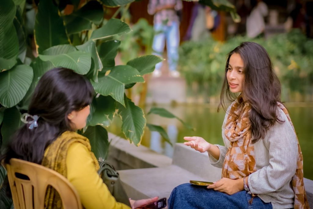 Two Indian women sitting on chairs talking and rebuilding social connections
