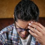 Indian man sitting alone feeling anxious and worried about financial concerns