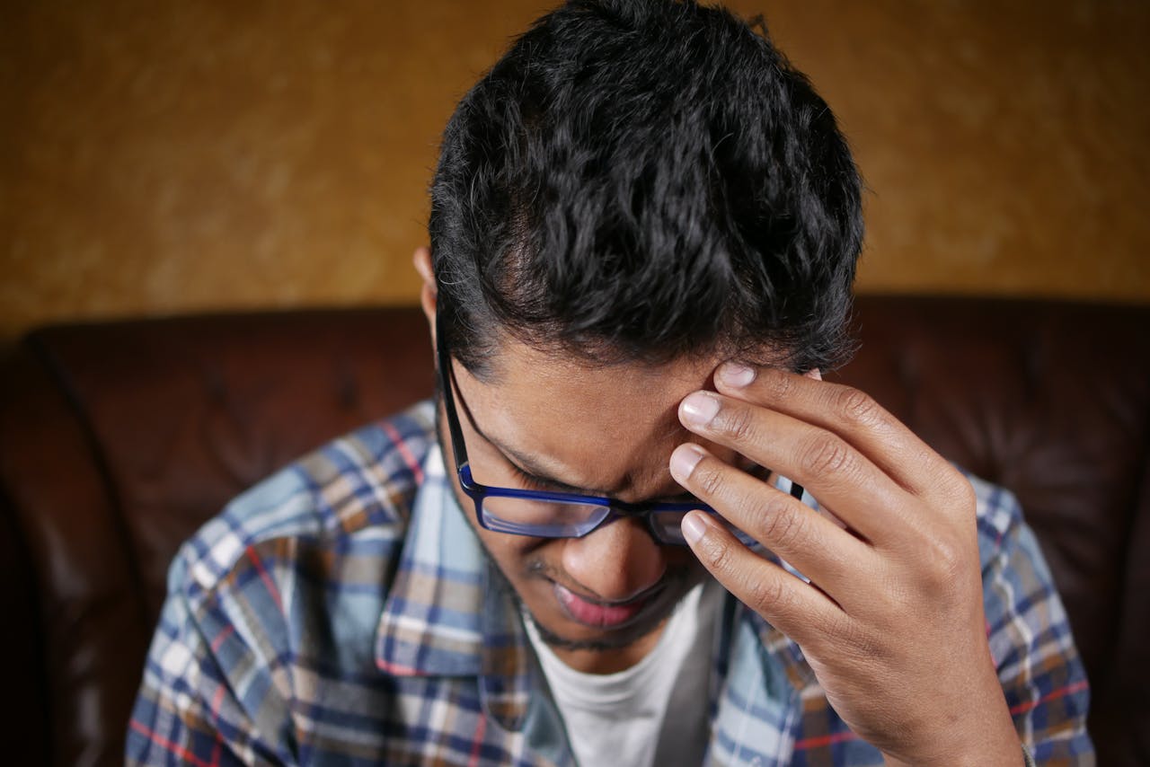Indian man sitting alone feeling anxious and worried about financial concerns